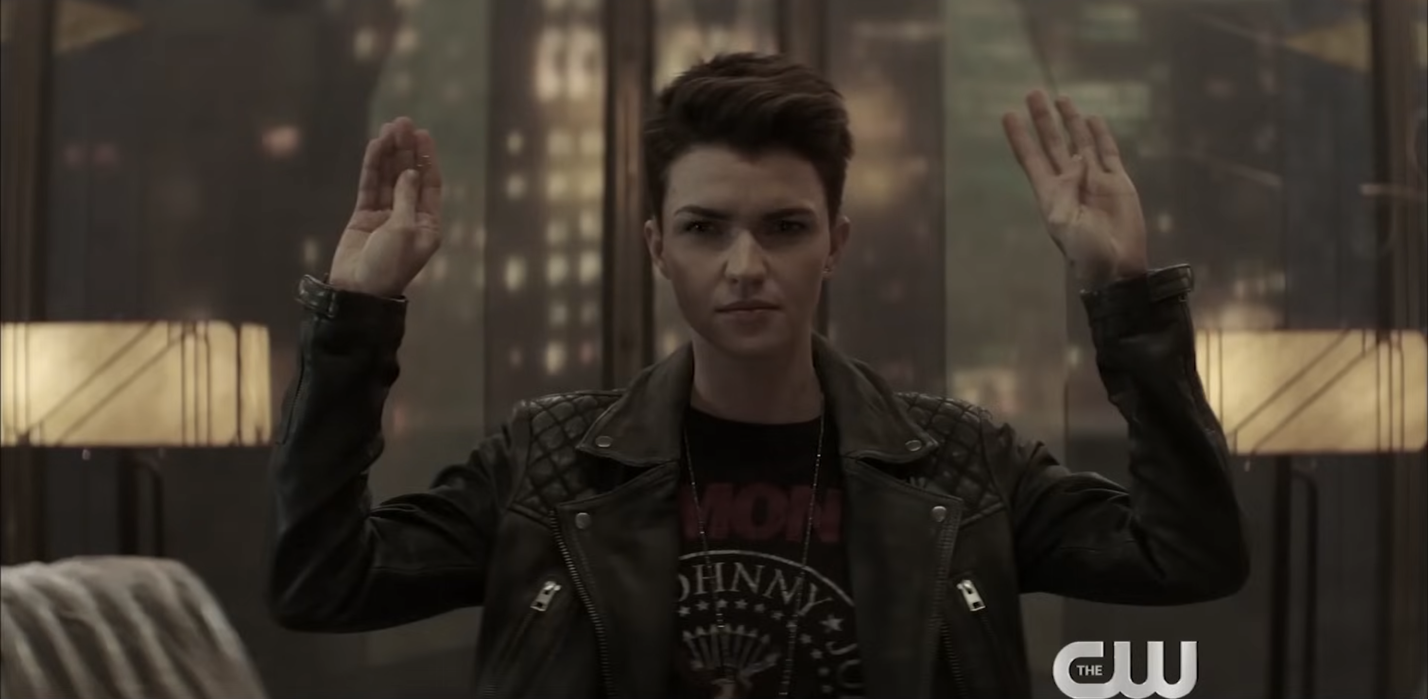 Person in a leather jacket, hands raised, with a cityscape backdrop