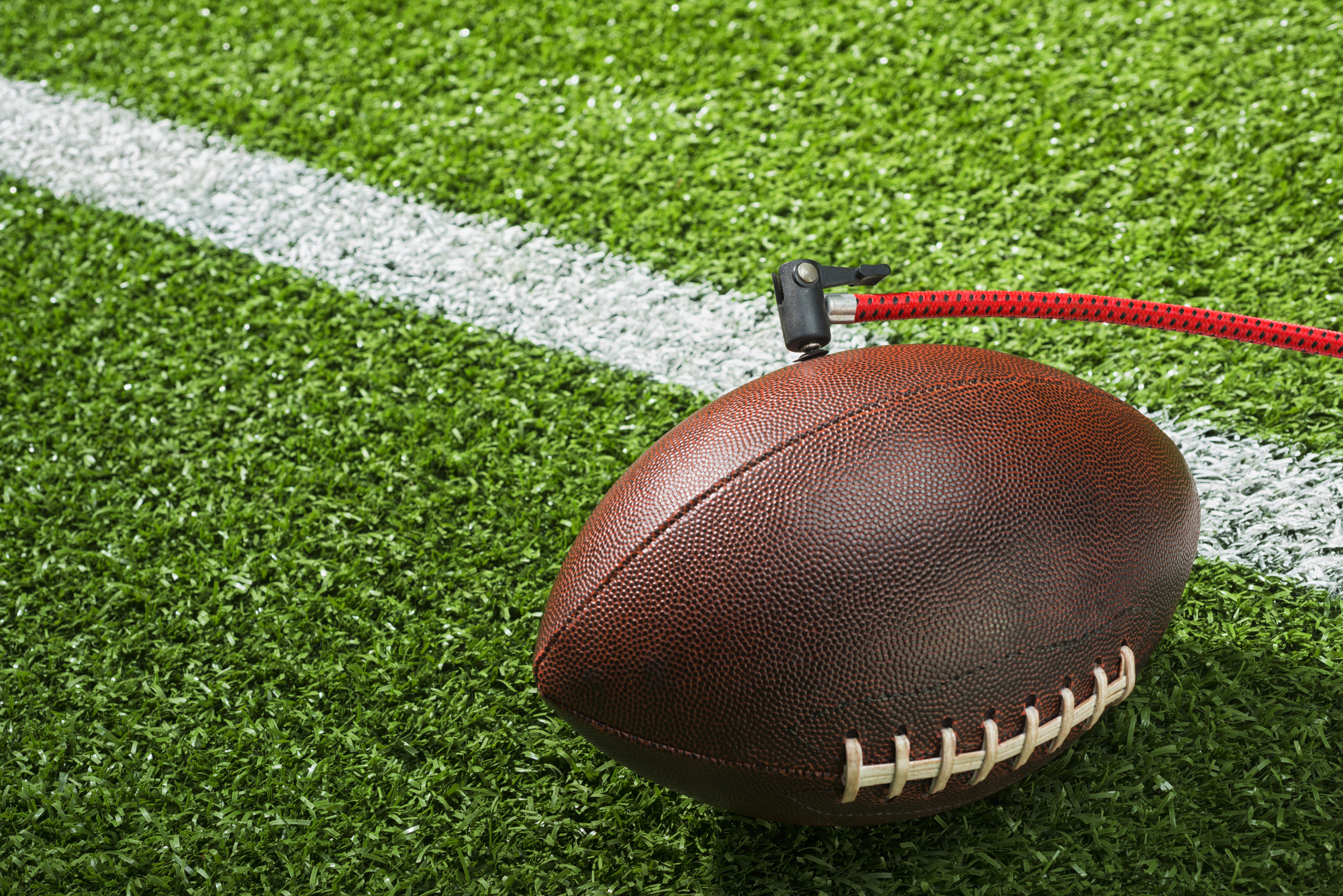 A football connected to an air pump on the sidelines of a field