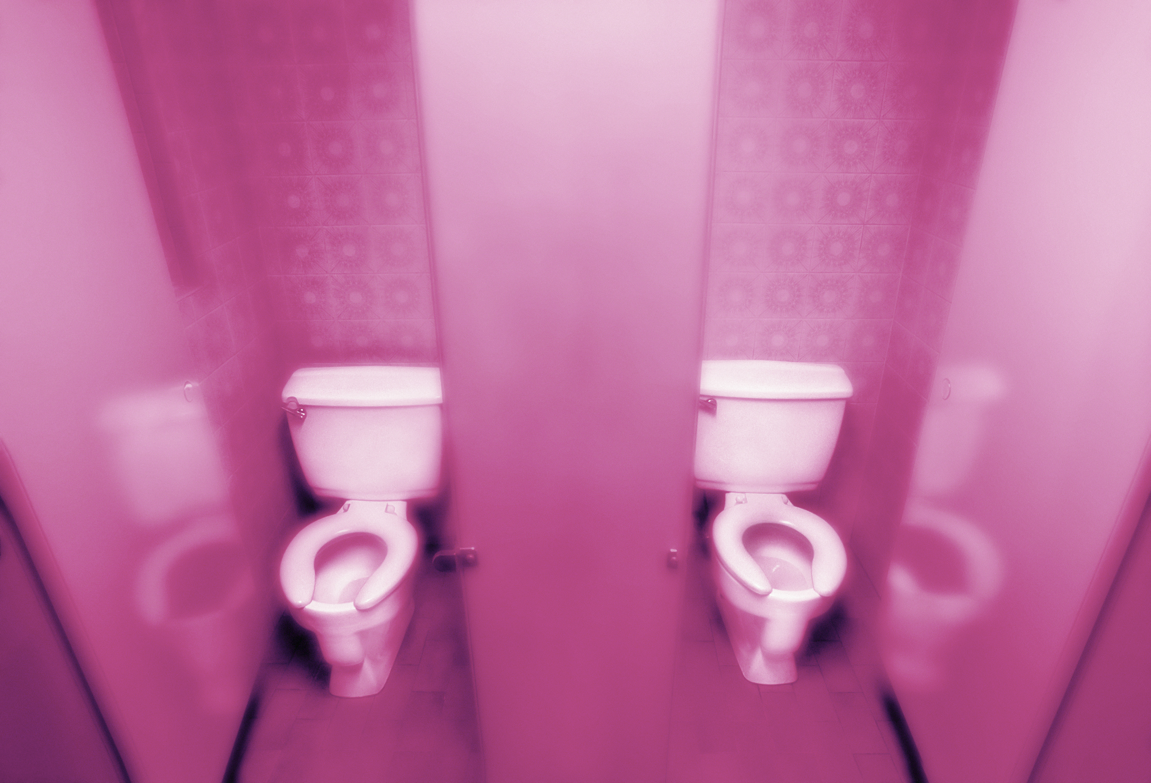 To toalettboder med synlige toaletter, reflektert i et speil, og skaper en symmetrisk visuell effekt
