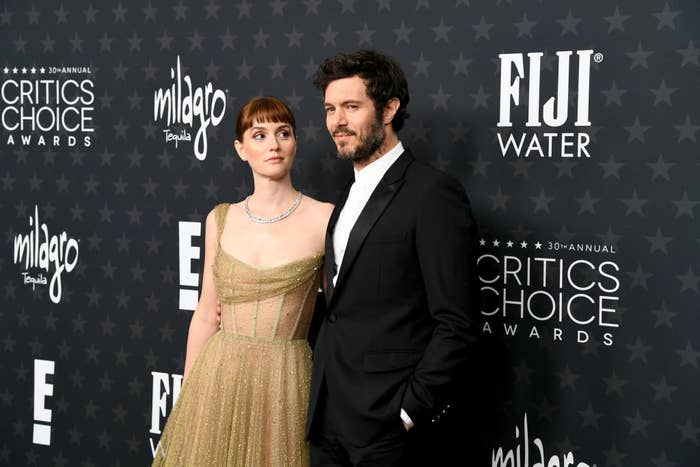 Two individuals pose on the Critics Choice Awards red carpet; one wears a sleeveless, sparkling gown and the other a black suit with a white shirt
