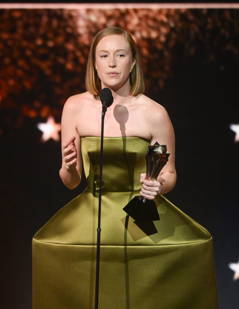 Person in structured, strapless dress holding an award and speaking into a microphone on stage