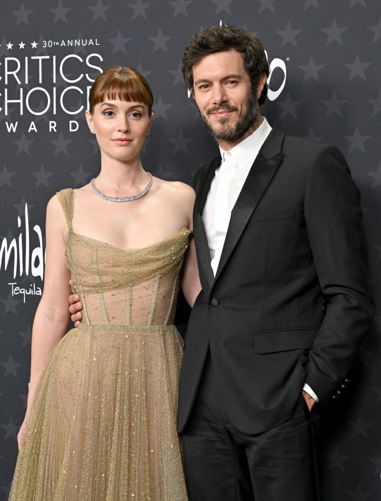 Two celebrities on the red carpet; one in a shimmering gown, the other in a classic tuxedo, posing together at the Critics Choice Awards