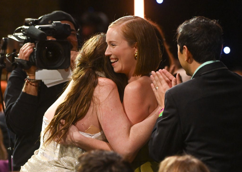 Two people hug joyfully in a crowd at an event, capturing a candid moment of celebration and applause