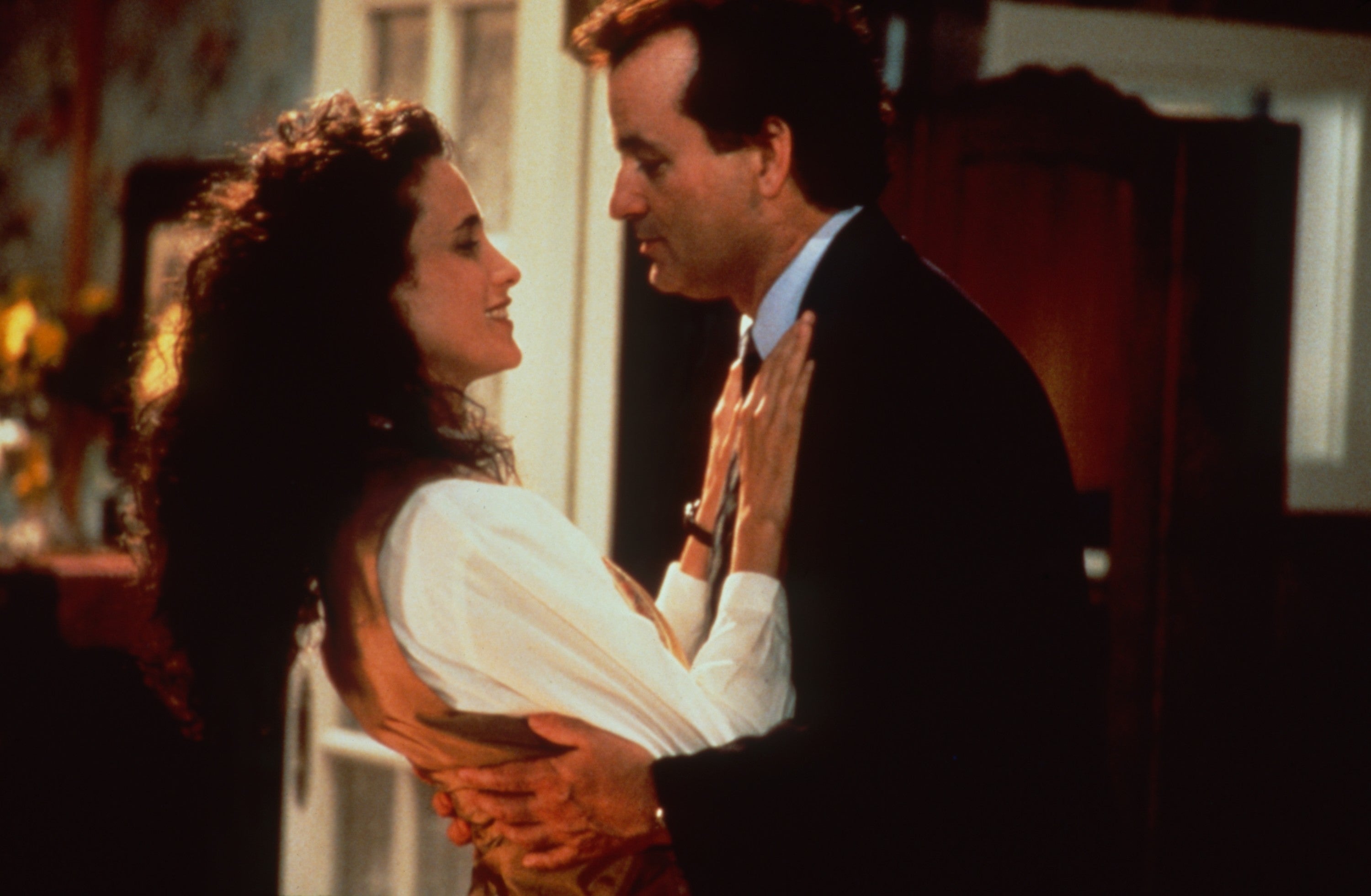 Two people stand closely, embracing and smiling at each other, suggesting a romantic or joyful moment
