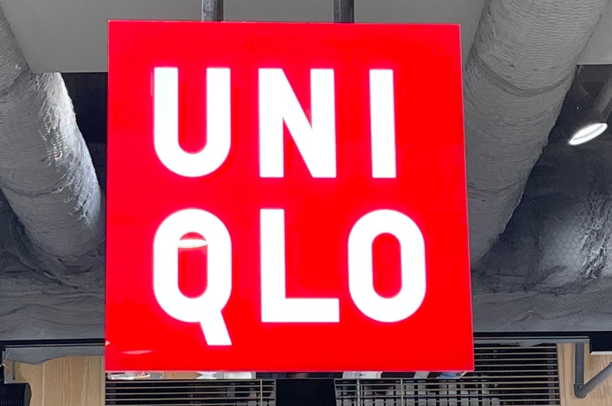 A red Uniqlo store sign hangs from the ceiling above folded clothing, with prices displayed on adjacent shelves