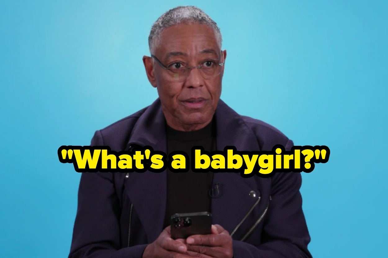 Person with short hair in a dark jacket holds a phone, posing a humorous question: "What's a babygirl?"