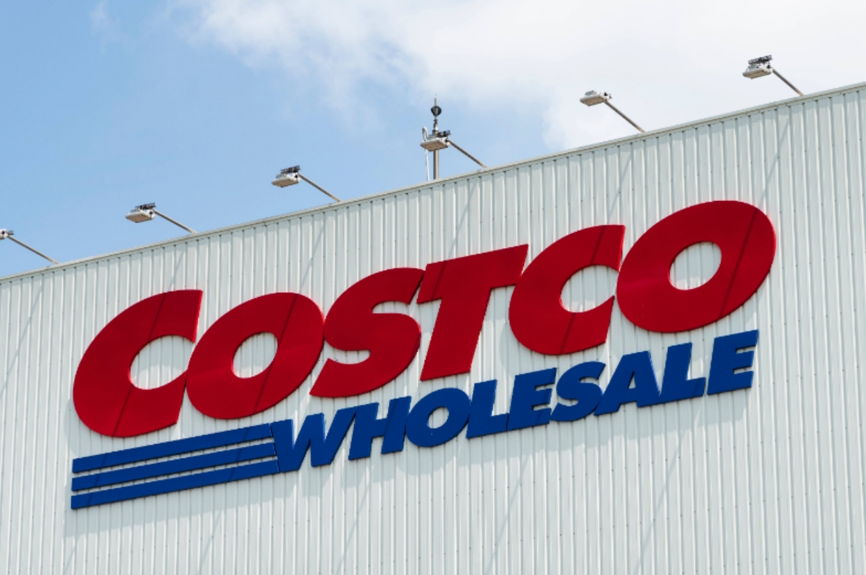 Costco Wholesale sign on the exterior of a building, viewed from below with a clear sky in the background