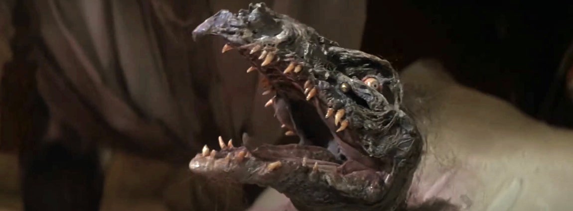 Animatronic creature with sharp teeth and a gaping mouth, featuring in a movie or TV show scene