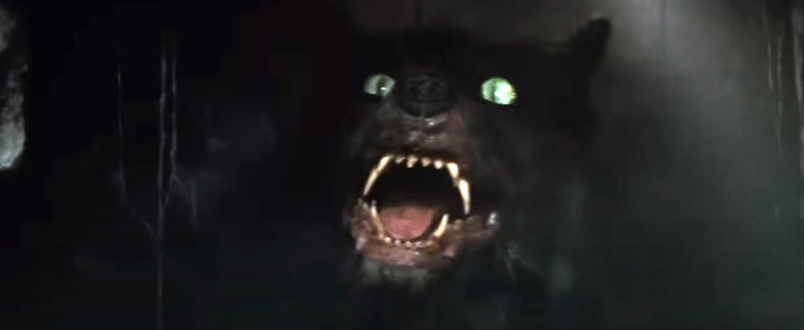 A menacing werewolf with glowing eyes and sharp teeth emerges from the darkness, snarling