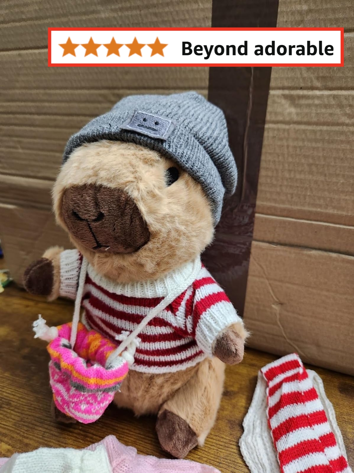 Stuffed animal capybara wearing a beanie and striped sweater with a small knitted bag