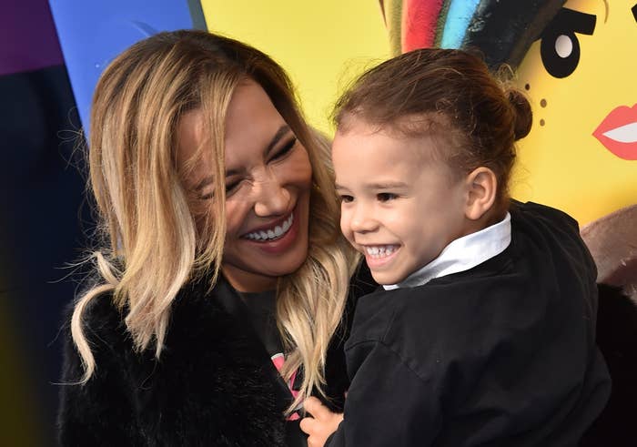 Naya Rivera smiling and holding Josey, both laughing, with a colorful background at an event