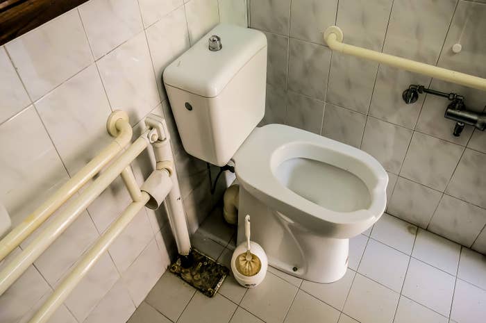 Bathroom with toilet and handrails along the walls, designed for accessibility