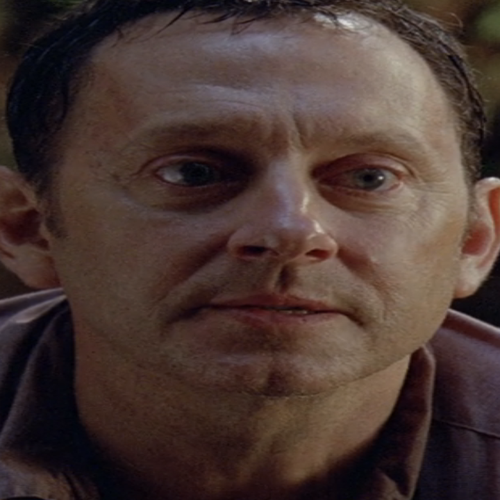 Michael Emerson is Ben Linus looking intently. The background is blurry with foliage