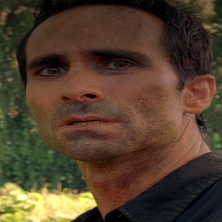 Néstor Carbonell as Richard in Lost standing outdoors, wearing a dark shirt, looking into the distance with a concerned expression