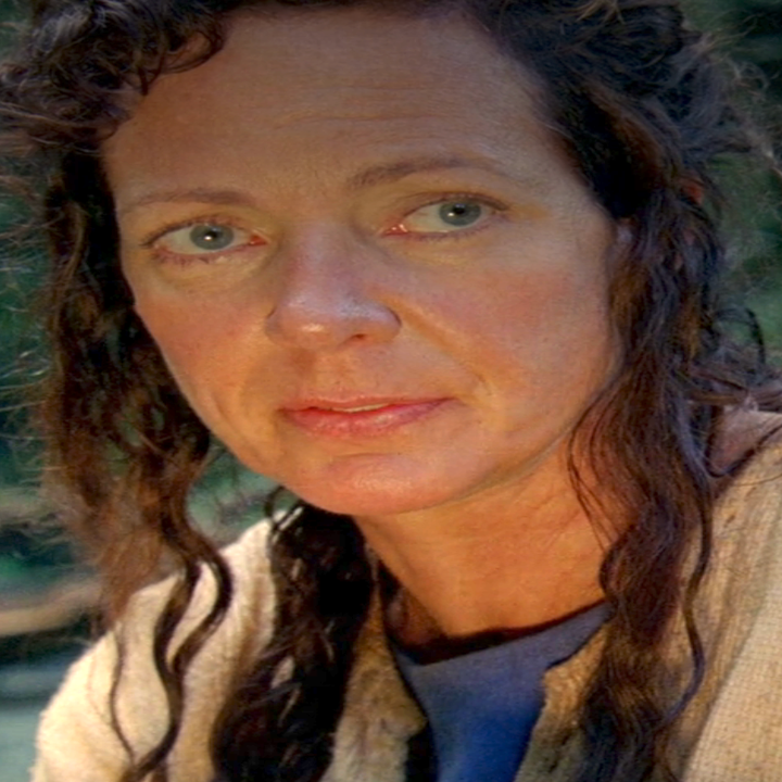 Allison Janney in Lost with long hair and neutral expression, wearing a simple, textured top, in an outdoor natural setting