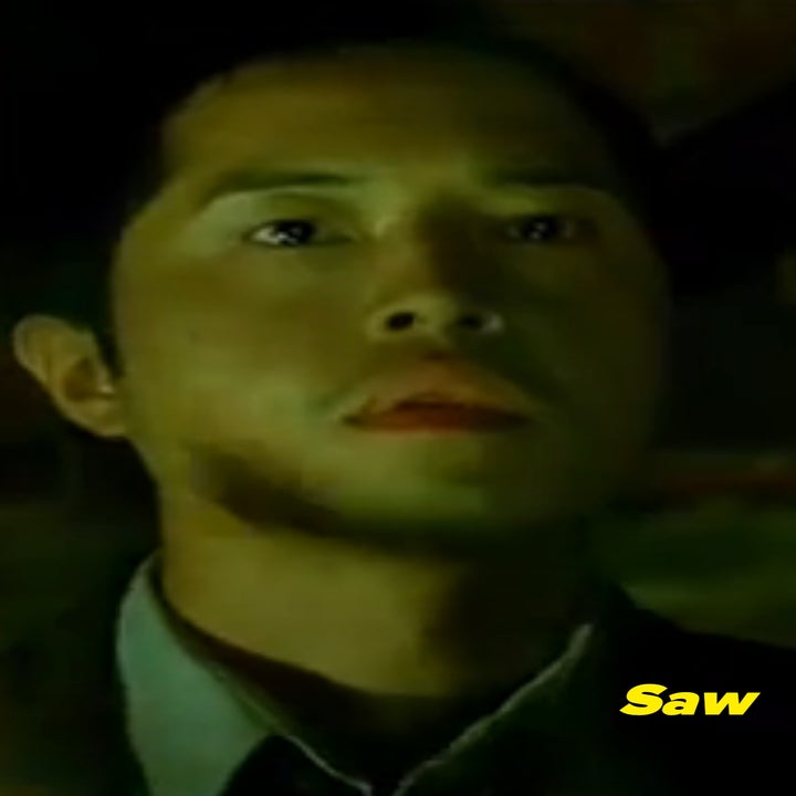 Ken Leung in Saw, in a dimly lit environment looking upward with a neutral expression