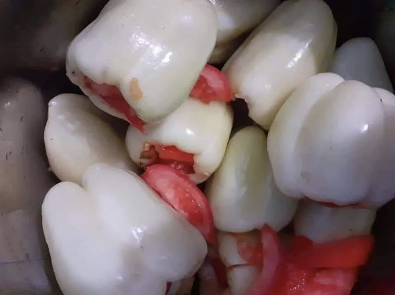 Several white bell peppers, some partially sliced, revealing red interior sections
