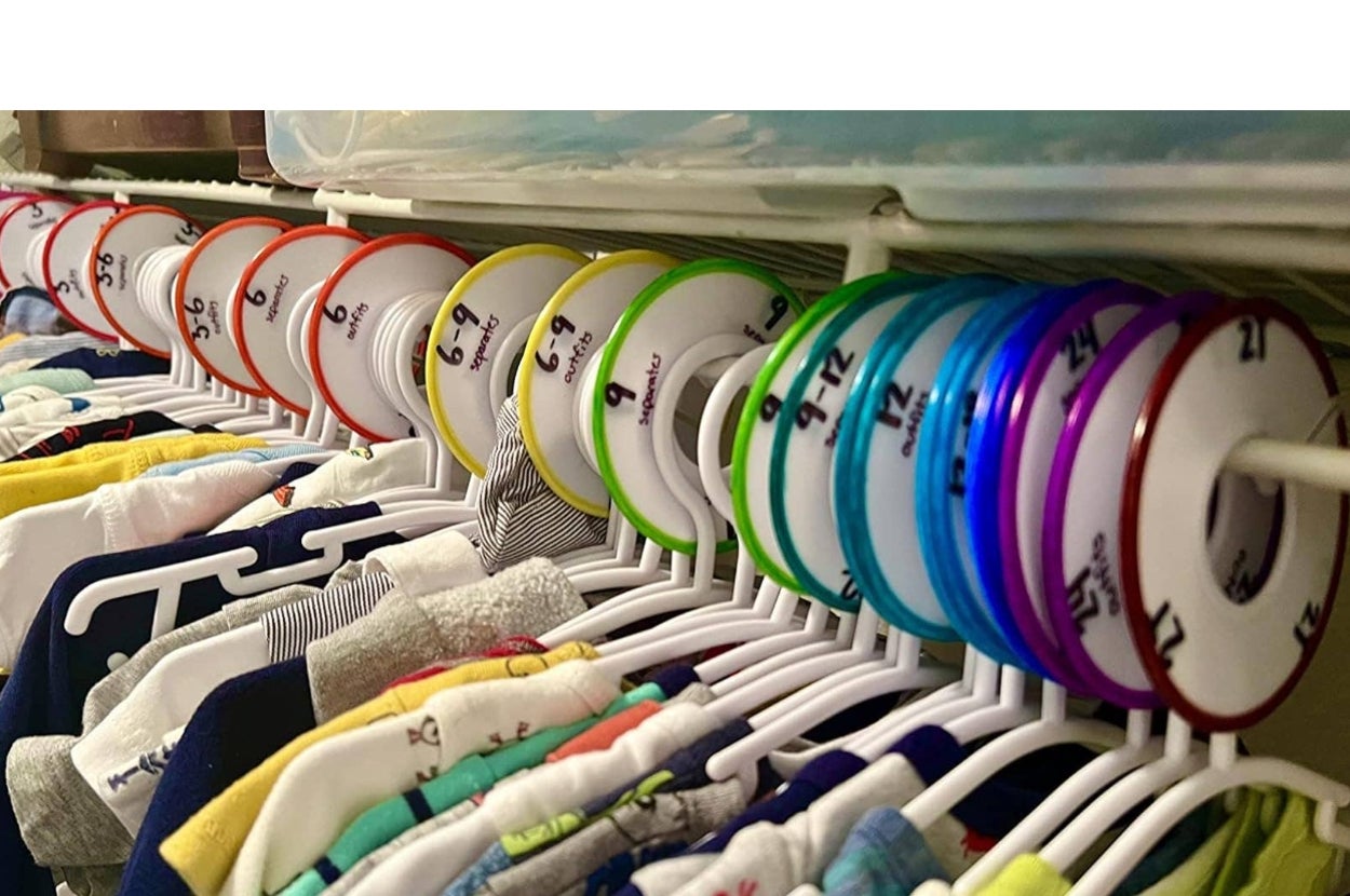 Closet with labeled clothes dividers on a rod, separating different sizes of hanging children's clothing