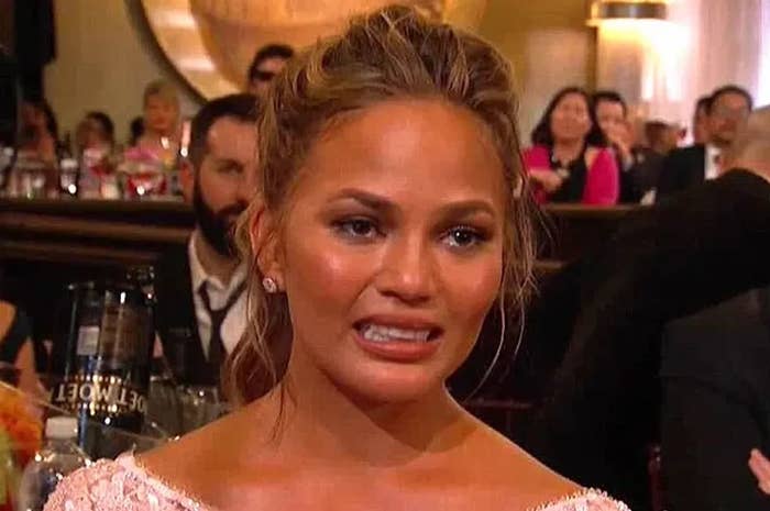 Chrissy Teigen at an awards show appears surprised with a slight grimace