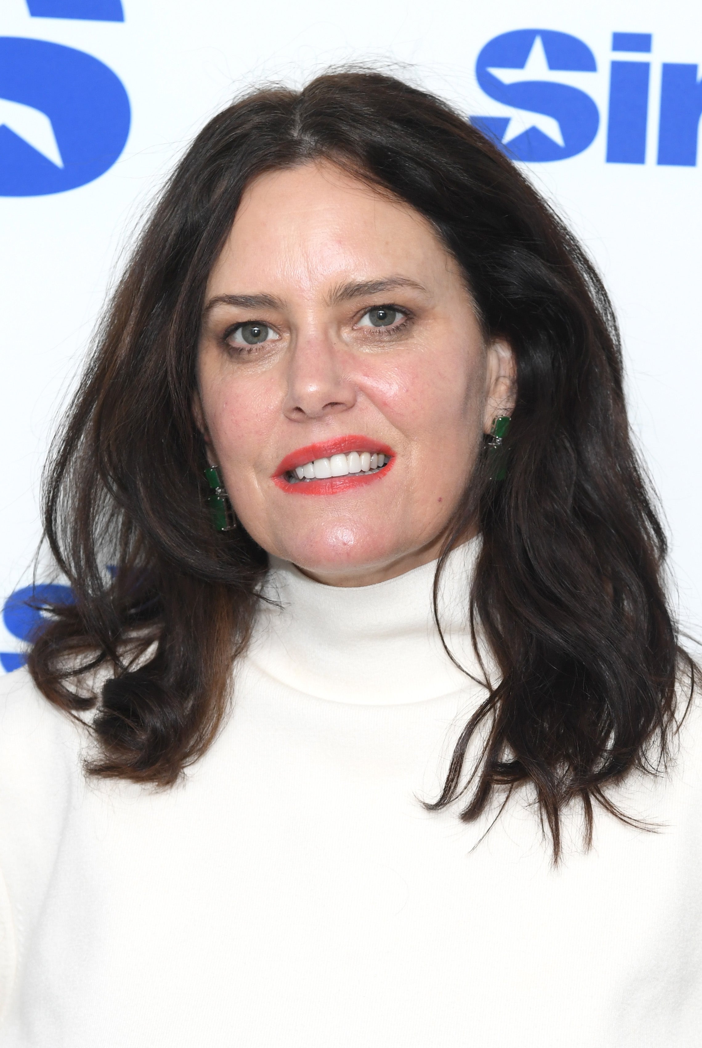 Ione Sky in a turtleneck top smiles at a media event