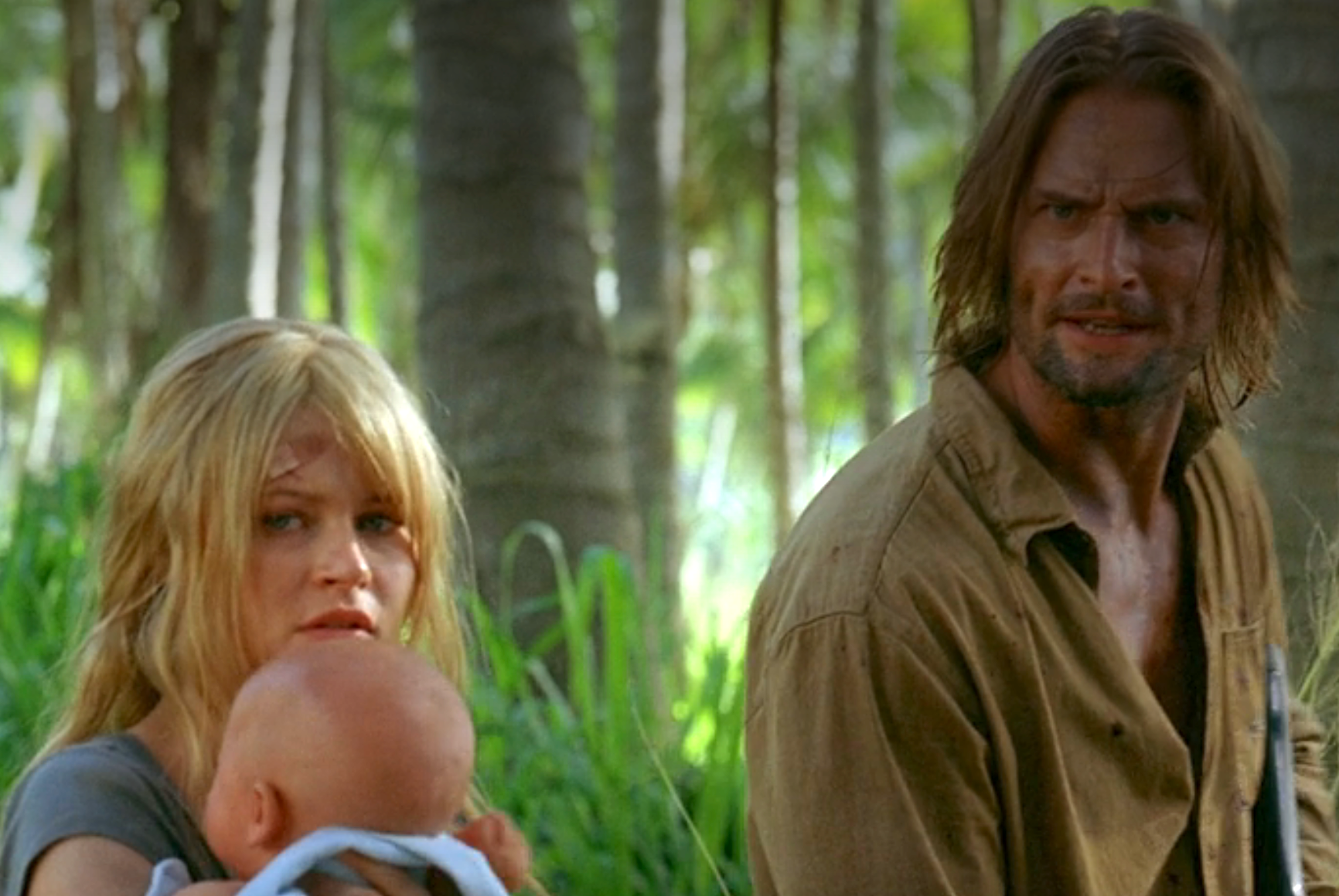 Claire holding a baby and Sawyer stand tensely in a jungle setting