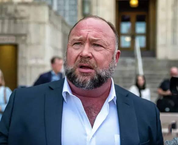 Alex Jones in a suit, standing outside a government building, expressing concern