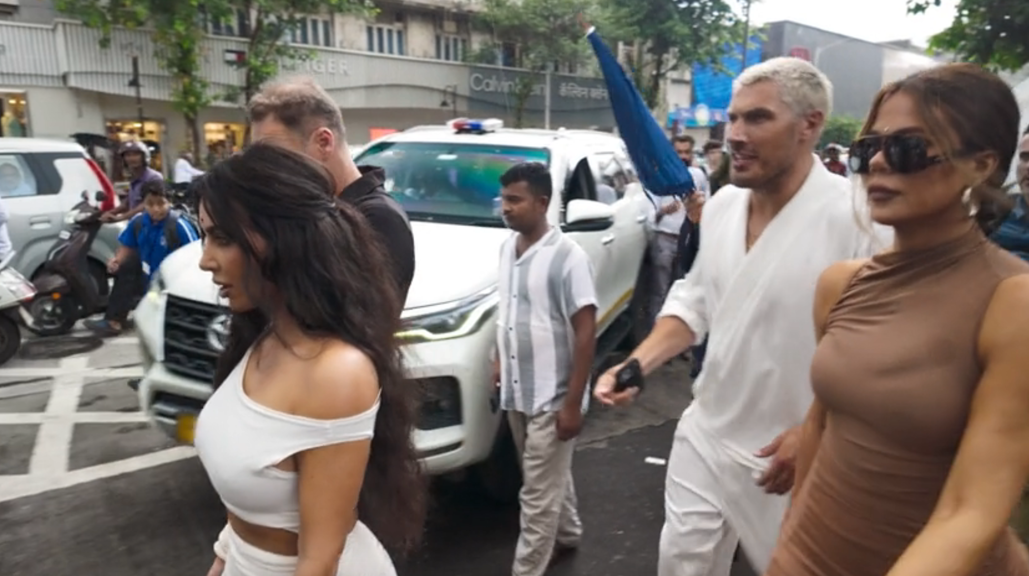 A group of people, including Kim and Khloe, walks down a busy street