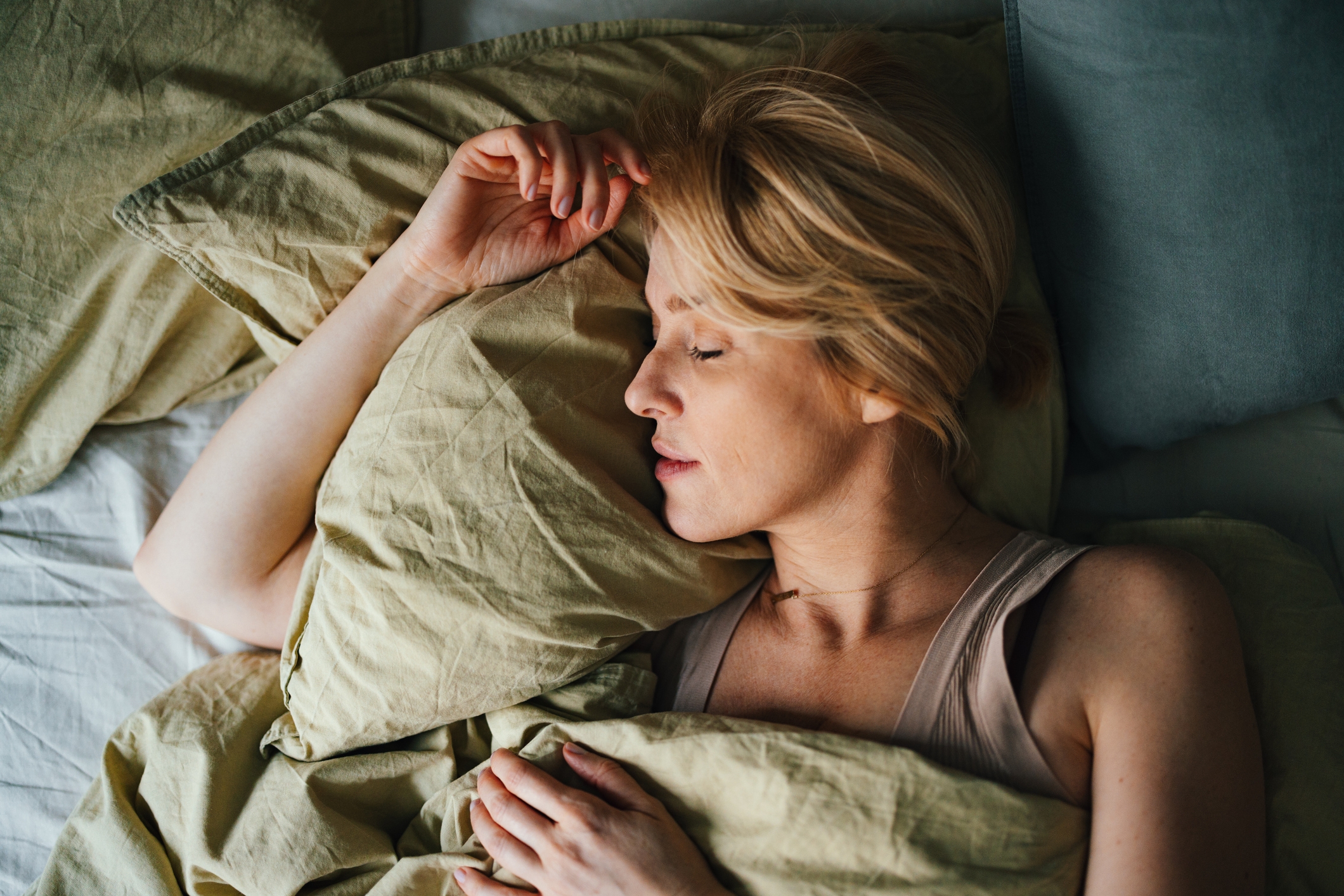 Person som fredelig sover på en pute, pakket inn i mykt sengetøy, formidler en rolig og avslappende atmosfære