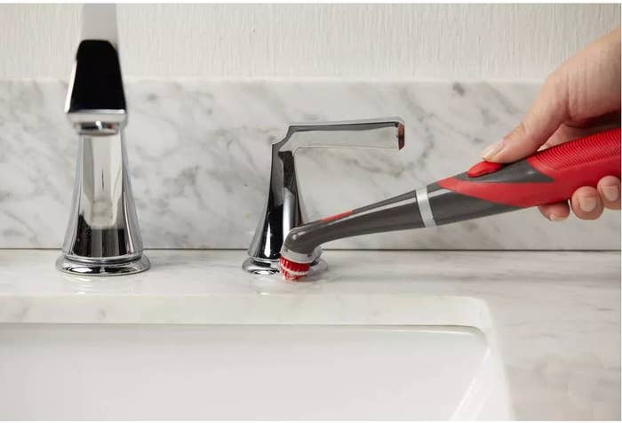 Hand utilizing a reddish powerfulness scrub brushwood to cleanable faucet basal connected marble sink