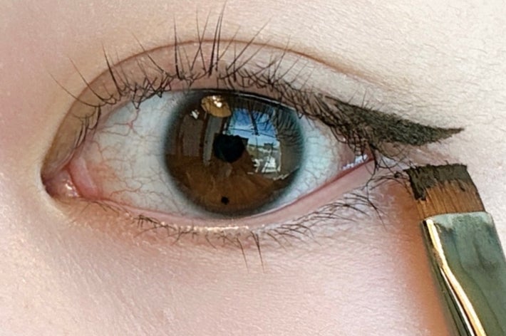 メイクブラシでアイライナーを描く様子を示す2段階の目元のクローズアップ。