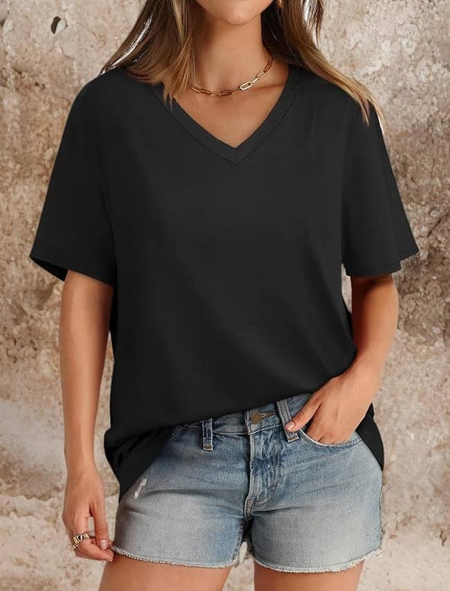 Person wearing a relaxed achromatic V-neck t-shirt with denim shorts