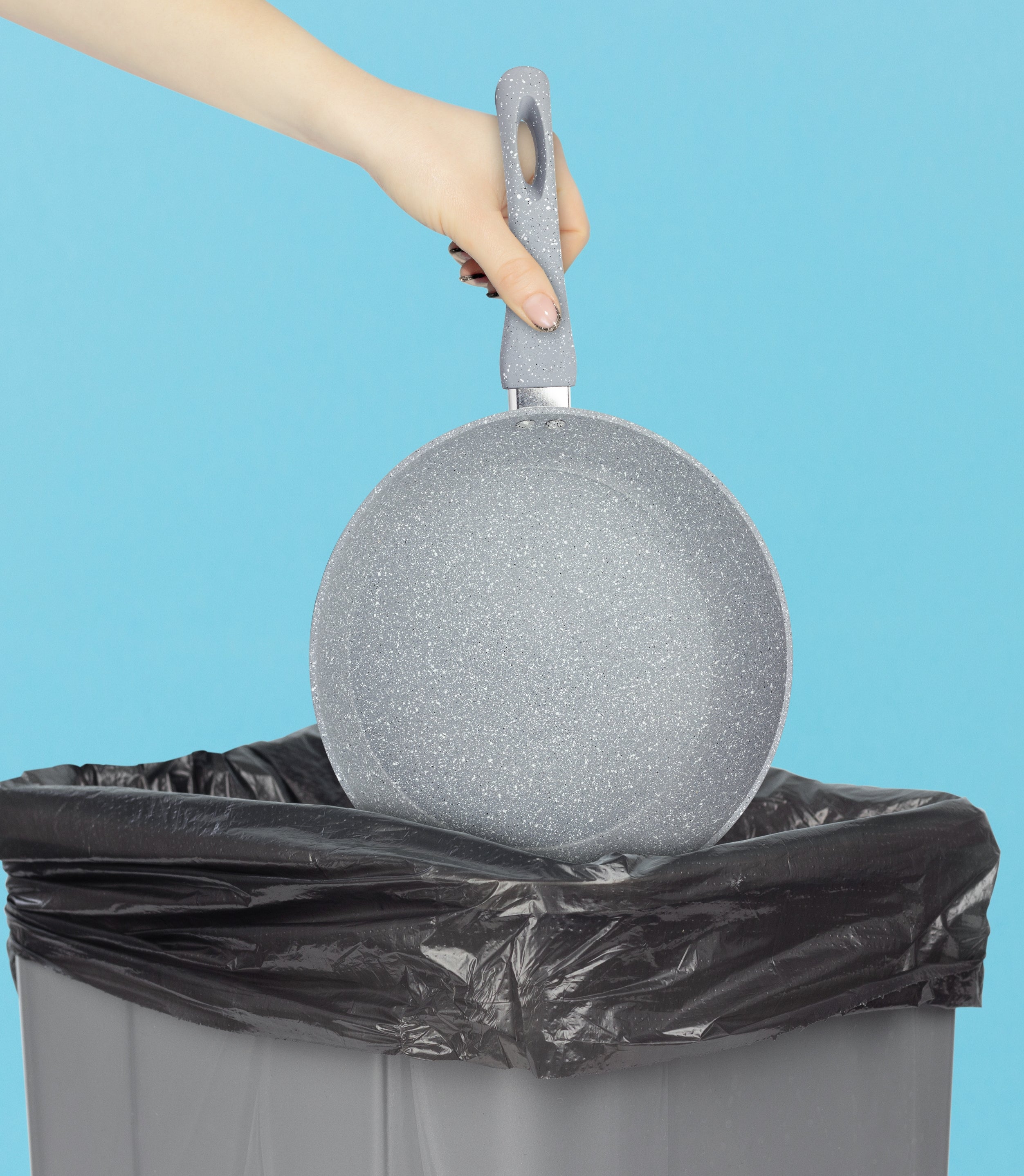 A hand is holding a frying pan above a trash can, as if about to discard it
