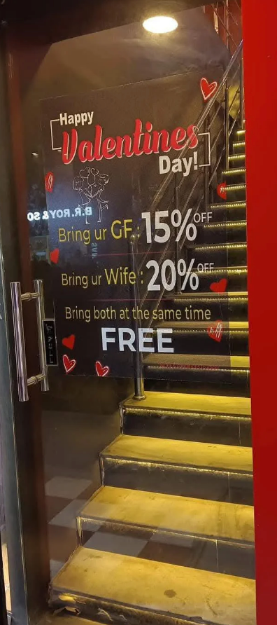 Glass door sign with Valentine's Day offers: 15% off with girlfriend, 20% off with wife, and free if both are brought together