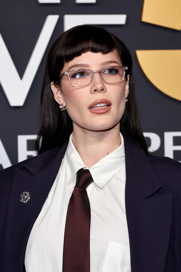 halsey with short bangs and glasses in formal attire, featuring a dark blazer, white shirt, and dark tie, attending a formal event