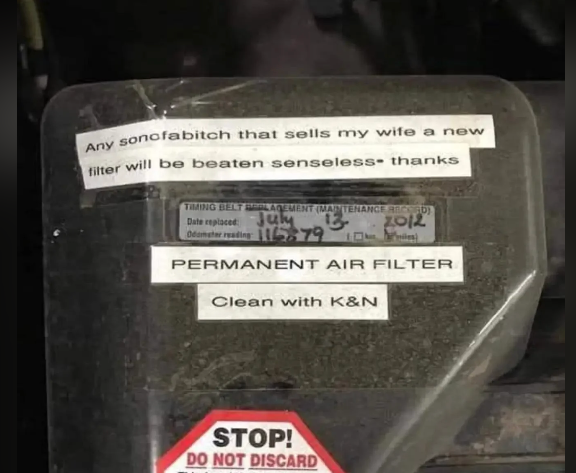Car engine compartment with a permanent air filter labeled &quot;PERMANENT AIR FILTER: Clean with K&amp;amp;N.&quot; Note above humorously warns not to replace it