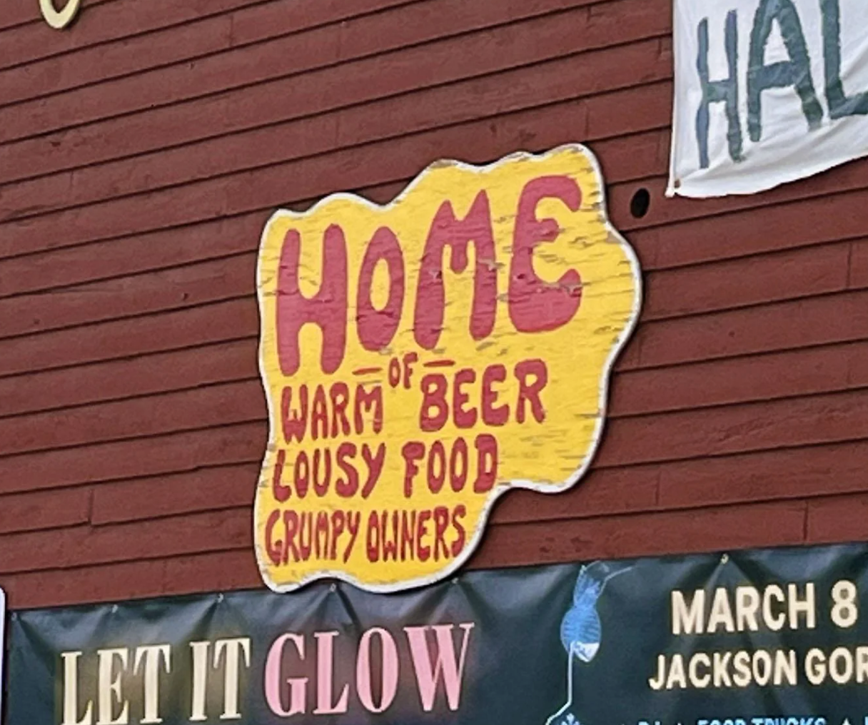 Sign on a building reads: &quot;Home of warm beer, lousy food, grumpy owners.&quot;