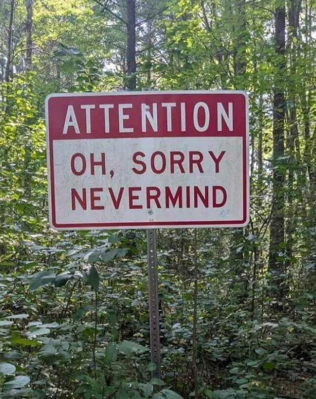 A humorous sign in a forest reads, &quot;Attention: Oh, Sorry Nevermind.&quot;