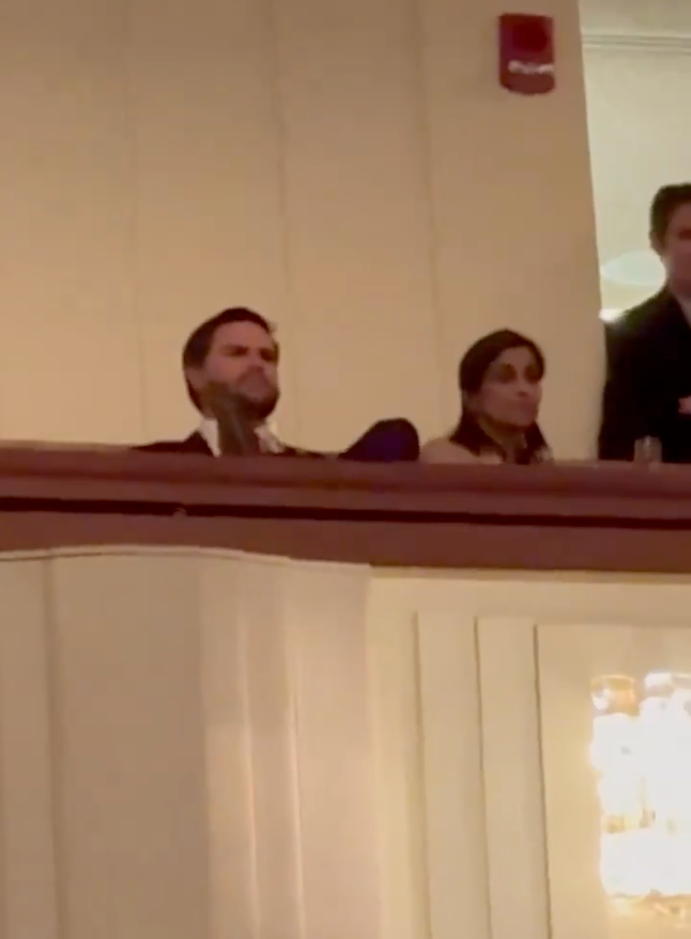 People seated in a theater balcony, observing a performance