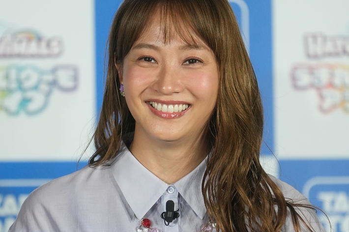 有名人がイベントでフリル付きのシャツを着て微笑んでいる。