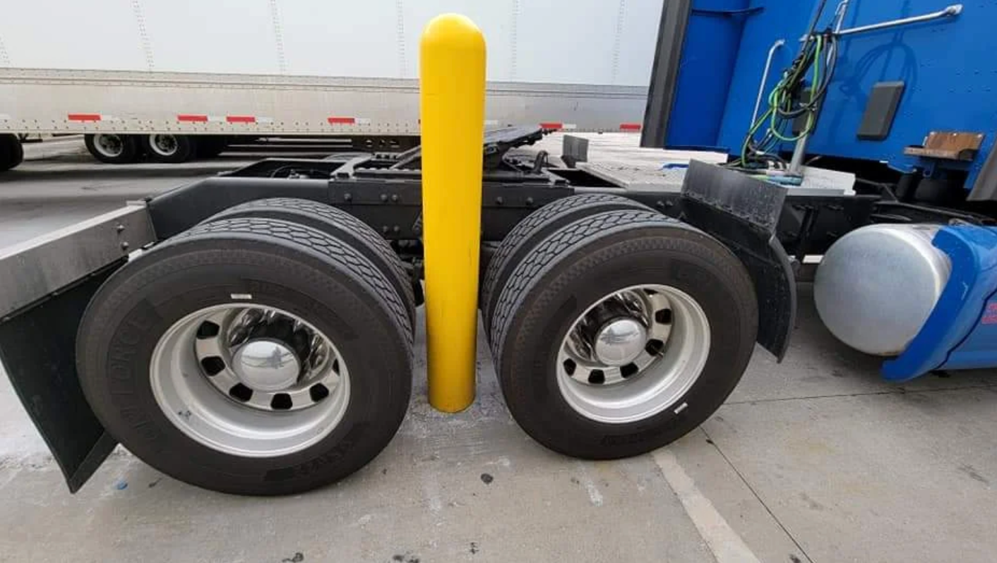 Truck parked with a yellow pole precisely between its rear wheels