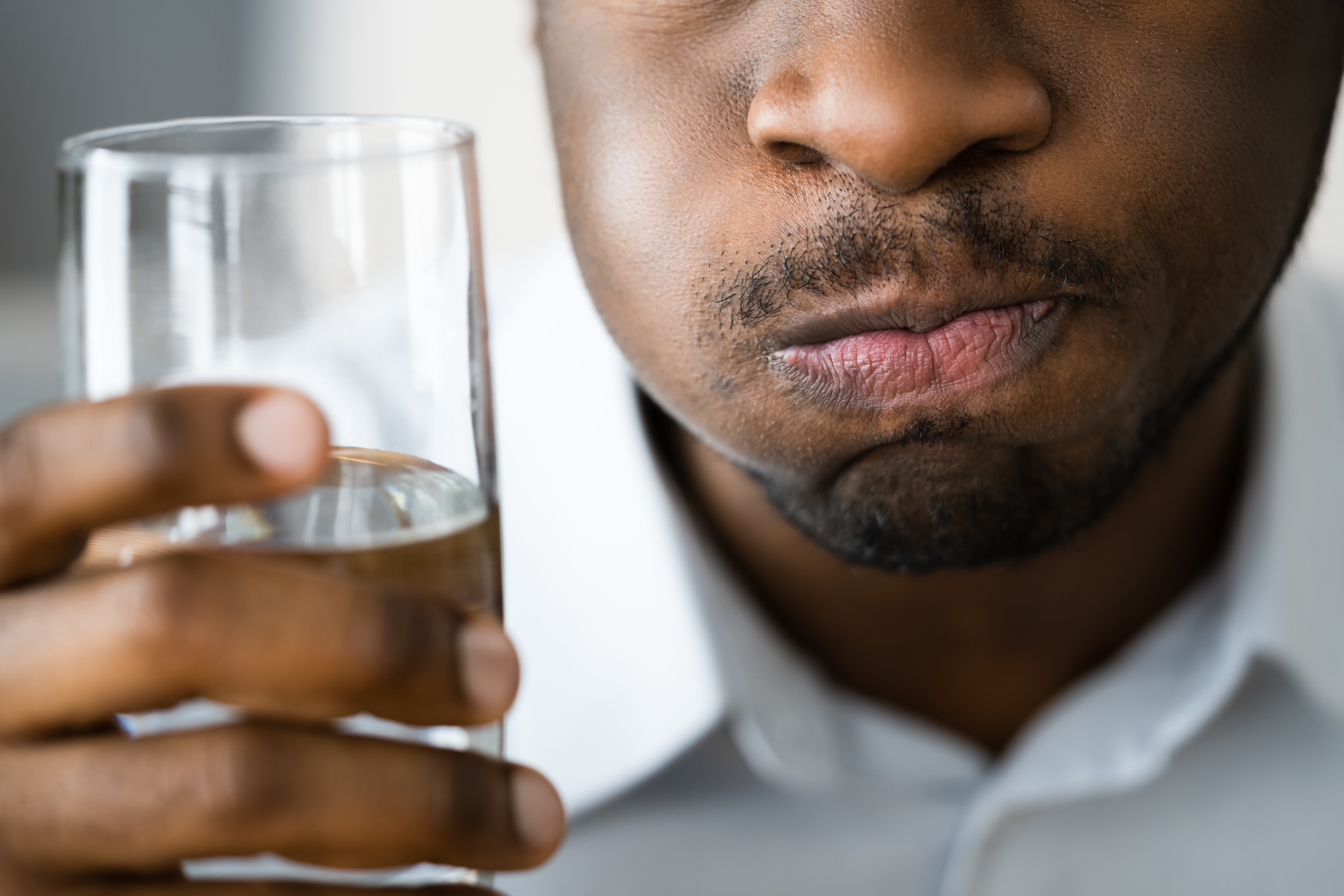 Person som holder et glass vann, ser ut til å svinge det i munnen, sannsynligvis relatert til munnhygiene eller smaker