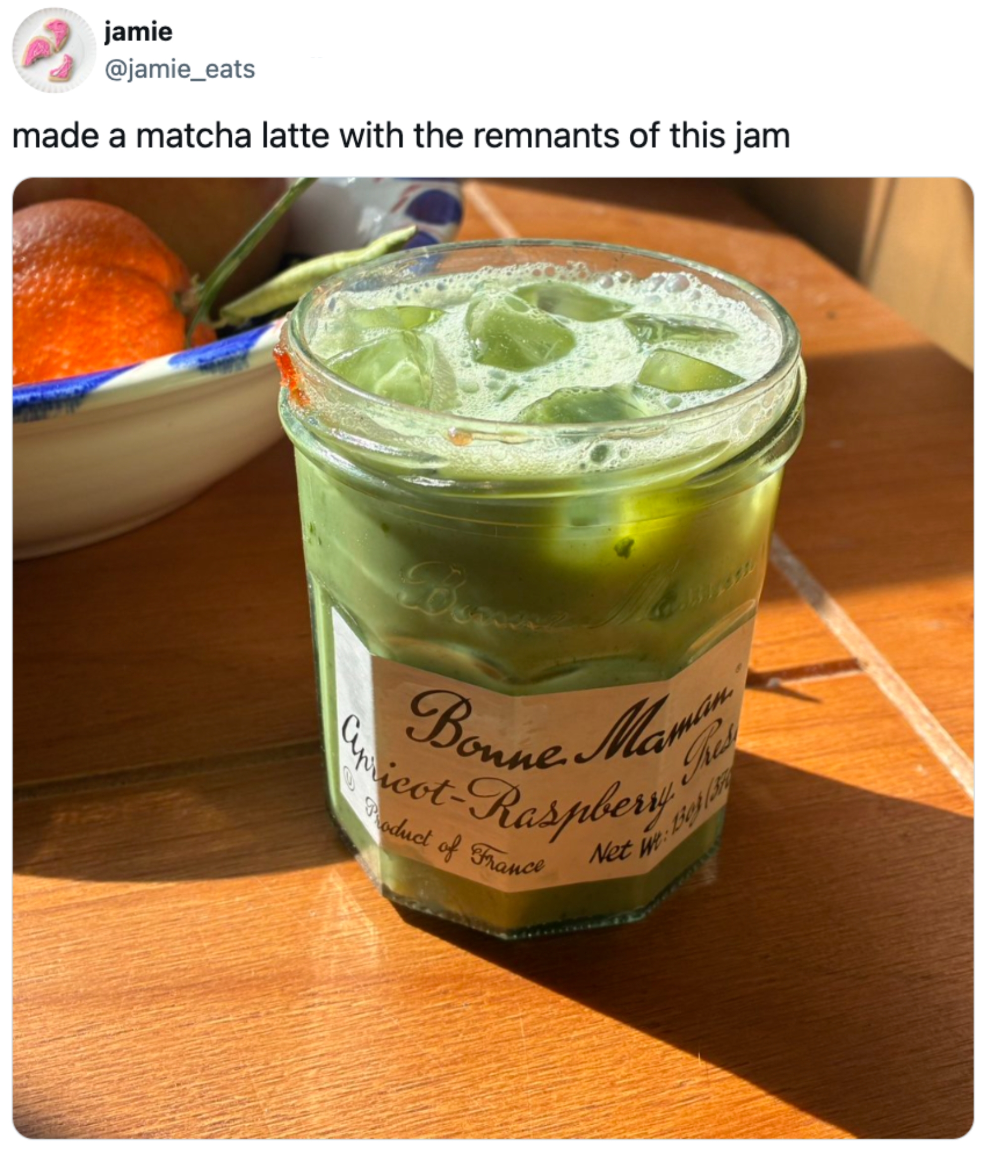 En krukke merket & quot; Bonne Maman aprikos-bringebær & quot; med en matcha latte inne. En fruktbolle er i bakgrunnen. Tekst: & quot; laget en matcha latte med restene av dette syltetøyet & quot;