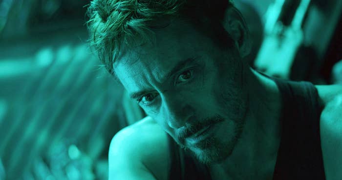 A man with a thoughtful expression, wearing a sleeveless top, against a futuristic backdrop