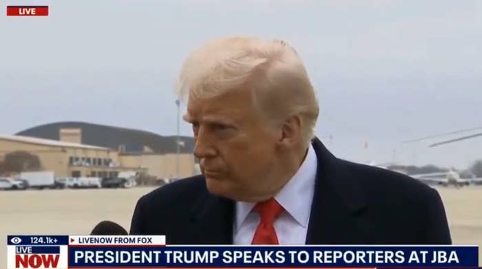 Trump speaking to reporters at an airport, with a microphone visible.
