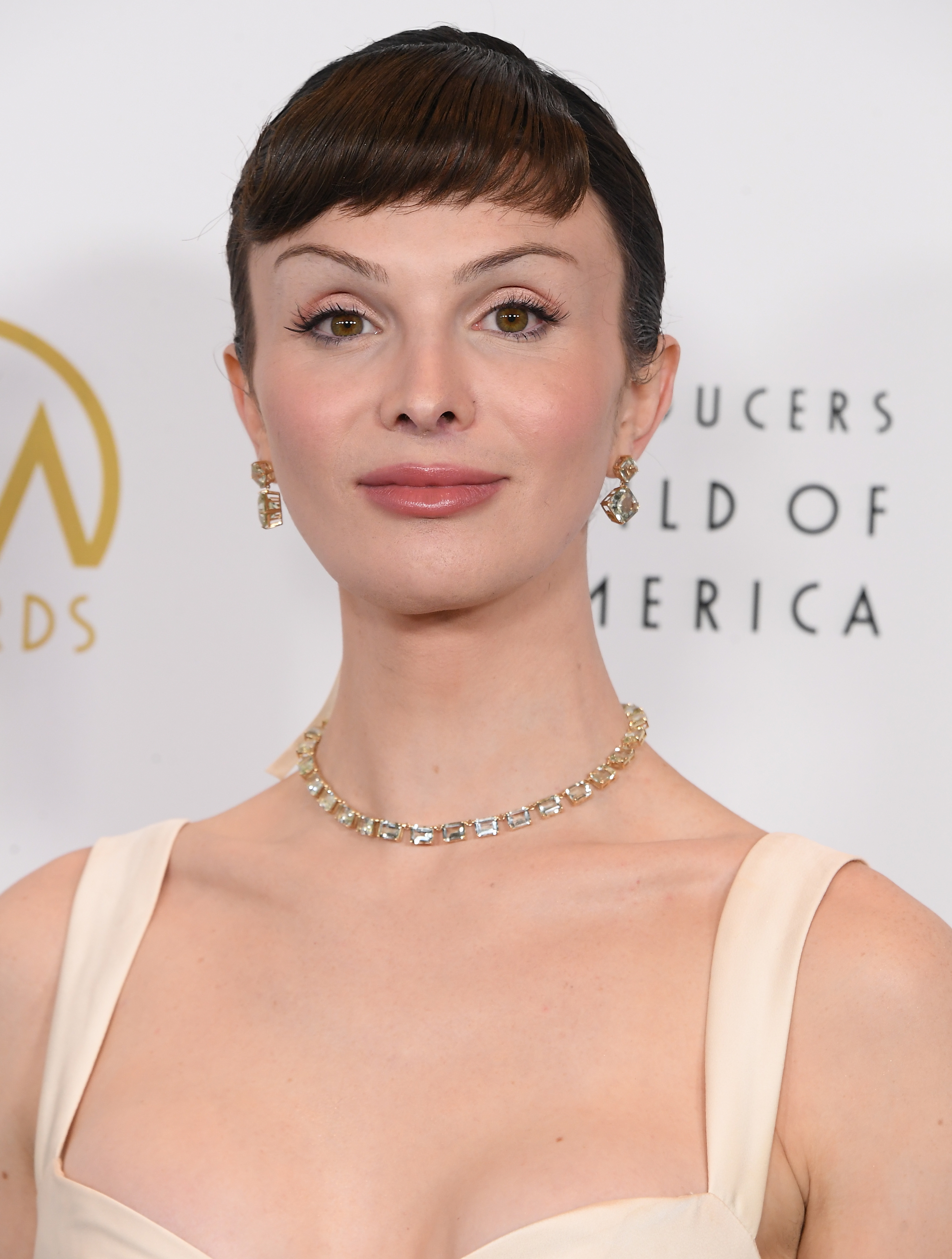 Dylan Mulvaney in formal attire with a necklace and earrings at a celebrity event