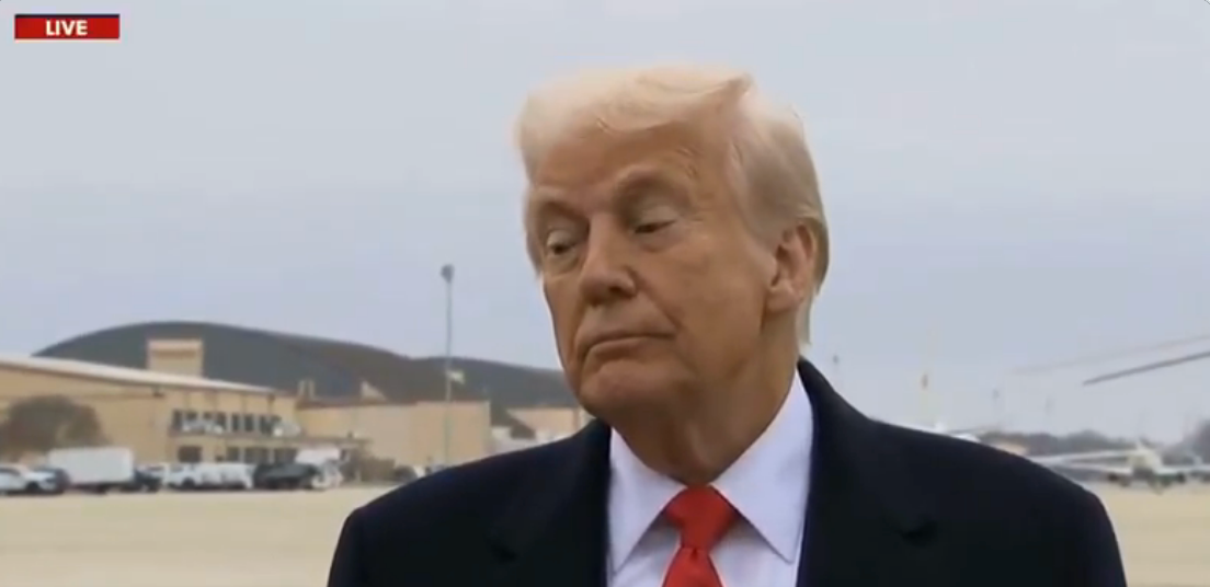 Trump in a suit and tie appears outside an airport with his eyebrows raised