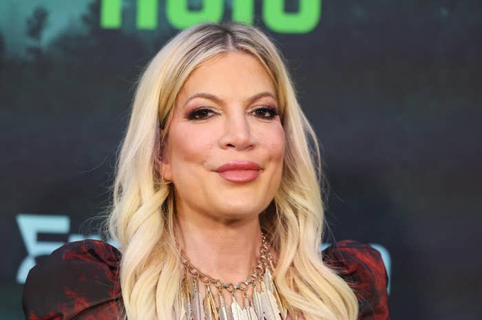Tori Spelling on the red carpet wearing a statement necklace and a stylish blouse with puffed shoulders