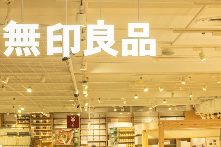 Shoppers browse inside a spacious, well-lit store with shelves of various products and a Japanese sign hanging from the ceiling