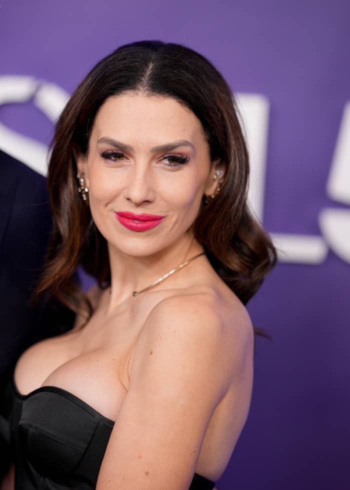 Person in elegant strapless gown poses confidently on a red carpet