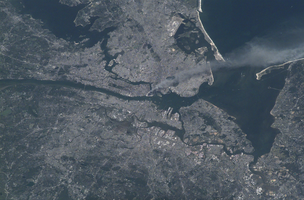 A satellite view of a densely populated cityscape surrounded by water, with visible land, rivers, and coastlines